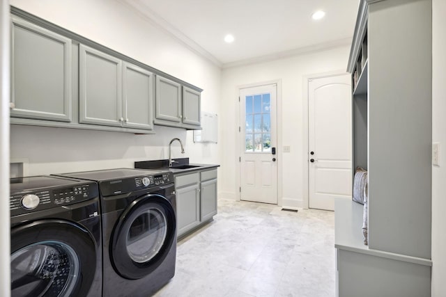 clothes washing area featuring cabinets, crown molding, washer and dryer, and sink