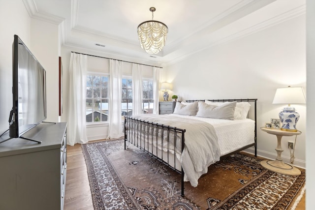 bedroom with dark hardwood / wood-style flooring, a tray ceiling, ornamental molding, and a chandelier