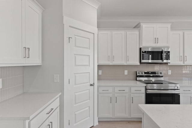 kitchen featuring white cabinetry, ornamental molding, appliances with stainless steel finishes, and backsplash