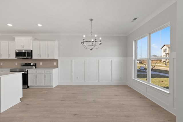 kitchen with pendant lighting, white cabinetry, stainless steel appliances, an inviting chandelier, and light hardwood / wood-style flooring