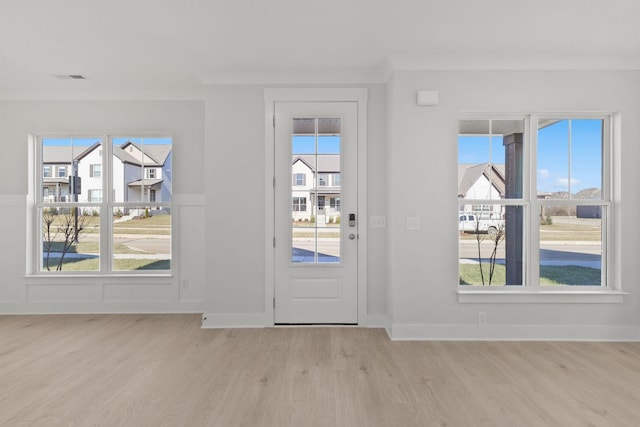 doorway to outside with crown molding, plenty of natural light, and light hardwood / wood-style floors