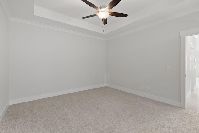 carpeted spare room featuring ornamental molding, a raised ceiling, and ceiling fan