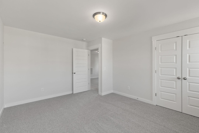 unfurnished bedroom featuring light colored carpet and a closet