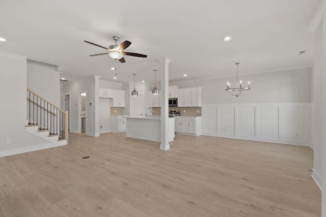 unfurnished living room featuring ornamental molding, sink, ceiling fan with notable chandelier, and light hardwood / wood-style floors