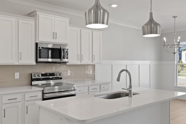 kitchen featuring stainless steel appliances, decorative light fixtures, and white cabinets