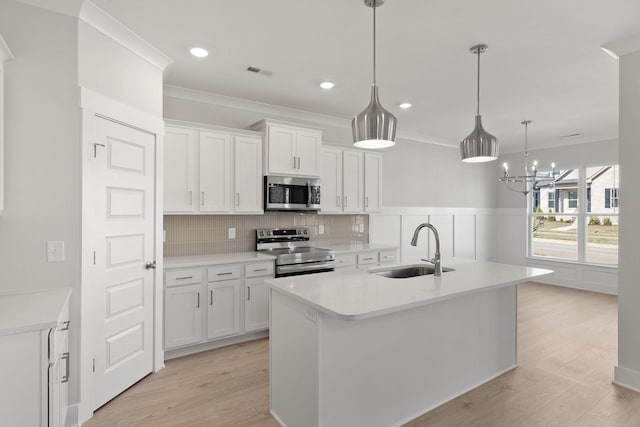 kitchen featuring sink, stainless steel appliances, an island with sink, and white cabinets