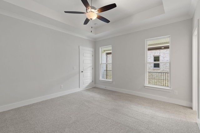 unfurnished room with a raised ceiling, ornamental molding, carpet floors, and ceiling fan