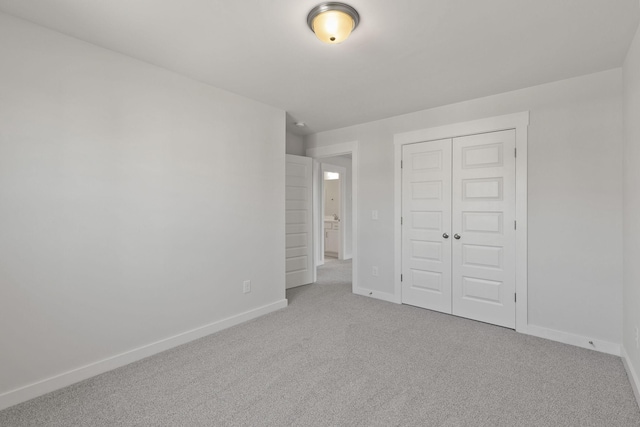 unfurnished bedroom with light colored carpet and a closet