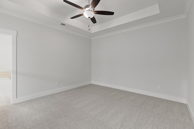 unfurnished room featuring a tray ceiling, ornamental molding, ceiling fan, and carpet