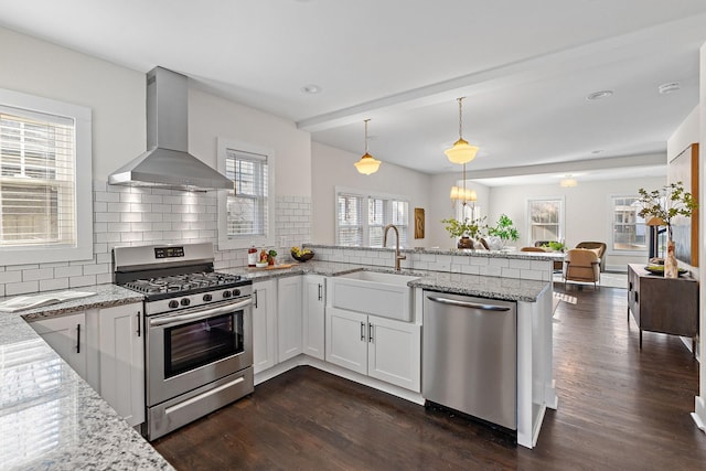 kitchen featuring sink, extractor fan, decorative light fixtures, stainless steel appliances, and white cabinets