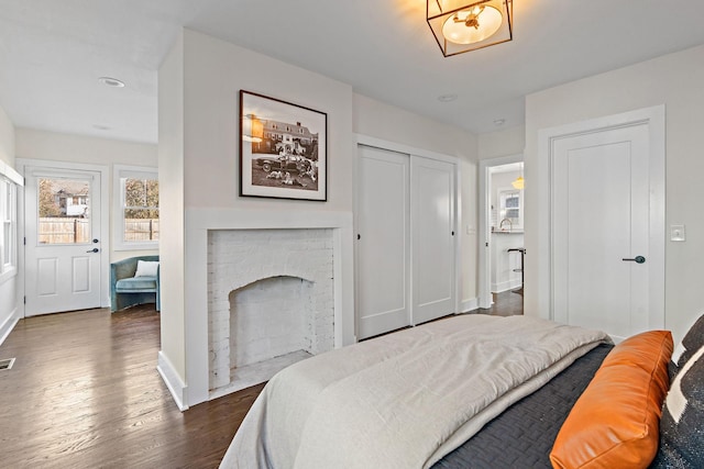 bedroom with dark wood-type flooring and a fireplace