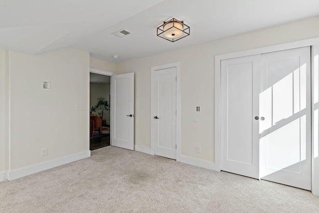 unfurnished bedroom featuring multiple closets and light carpet