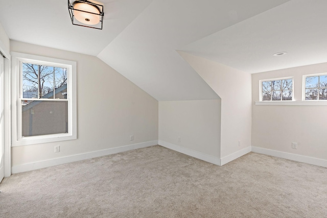 bonus room with light carpet and vaulted ceiling