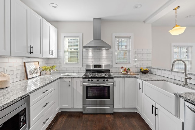 kitchen featuring appliances with stainless steel finishes, sink, wall chimney range hood, and white cabinets