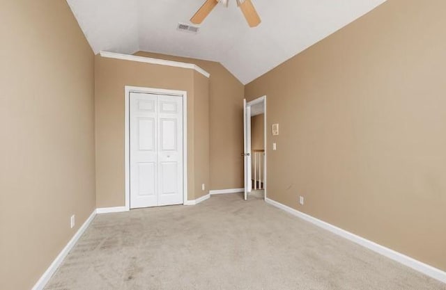 unfurnished bedroom with ceiling fan, a closet, vaulted ceiling, and light carpet