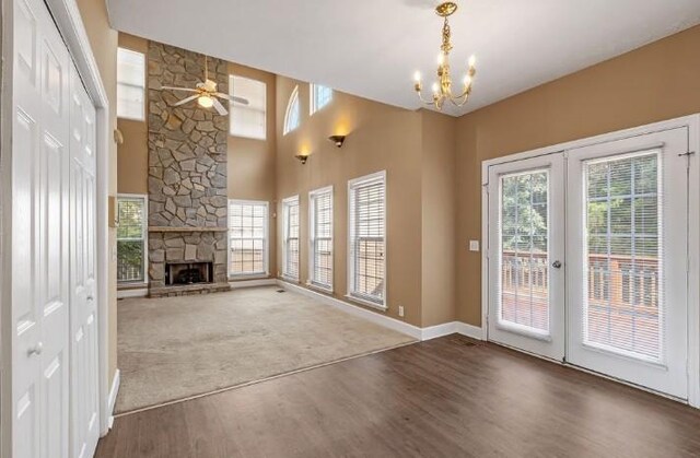 unfurnished living room with dark wood-type flooring, plenty of natural light, french doors, and a stone fireplace