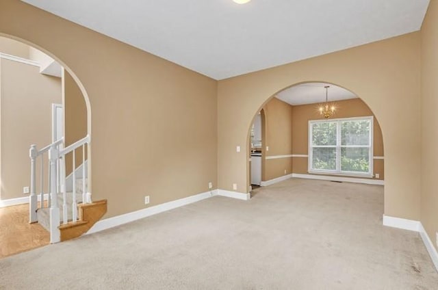 carpeted spare room featuring an inviting chandelier