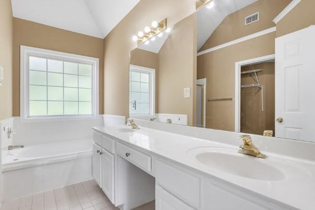 bathroom with tile patterned flooring, vaulted ceiling, vanity, and a tub to relax in