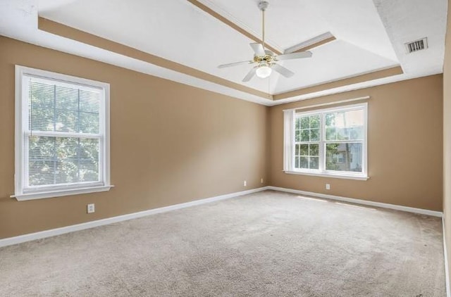 unfurnished room featuring a raised ceiling, ceiling fan, and carpet flooring