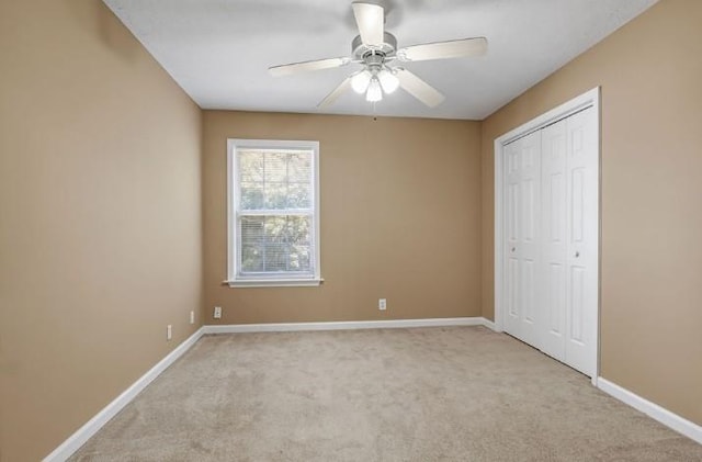 unfurnished bedroom featuring light carpet, ceiling fan, and a closet