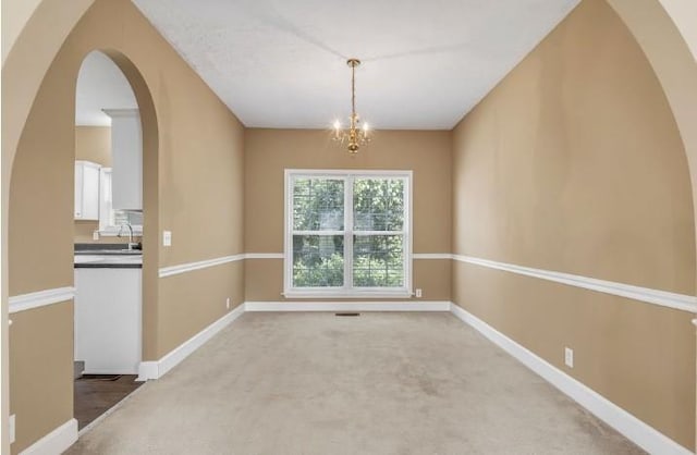 unfurnished dining area featuring carpet floors, sink, and a notable chandelier