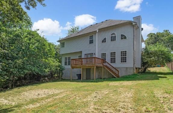 back of house with a wooden deck and a yard