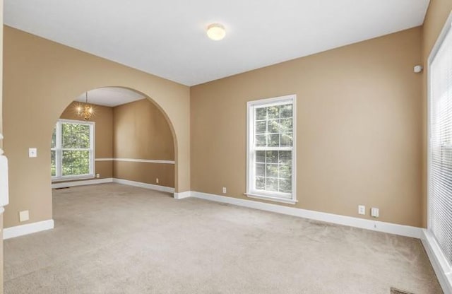 unfurnished room with light carpet and a notable chandelier