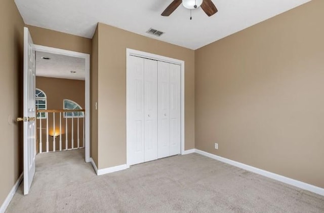 unfurnished bedroom with light carpet, ceiling fan, and a closet