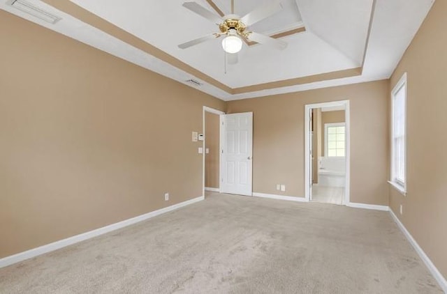 carpeted empty room with a raised ceiling and ceiling fan