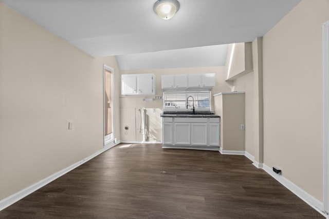 unfurnished living room with sink, dark hardwood / wood-style flooring, and vaulted ceiling