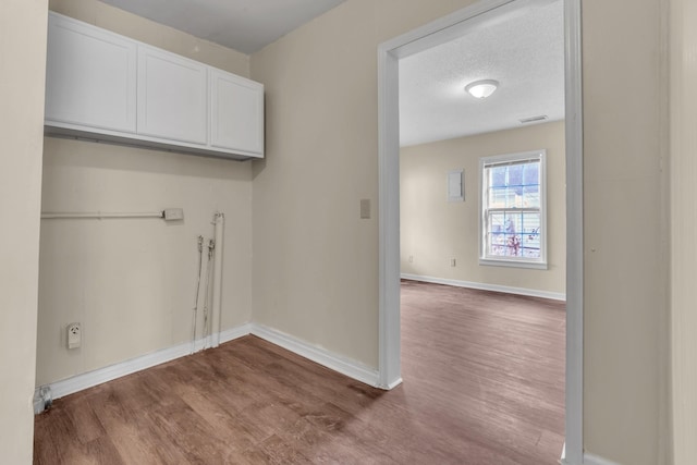 laundry area featuring hardwood / wood-style flooring, cabinets, and a textured ceiling