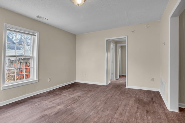 spare room featuring dark hardwood / wood-style floors and a textured ceiling