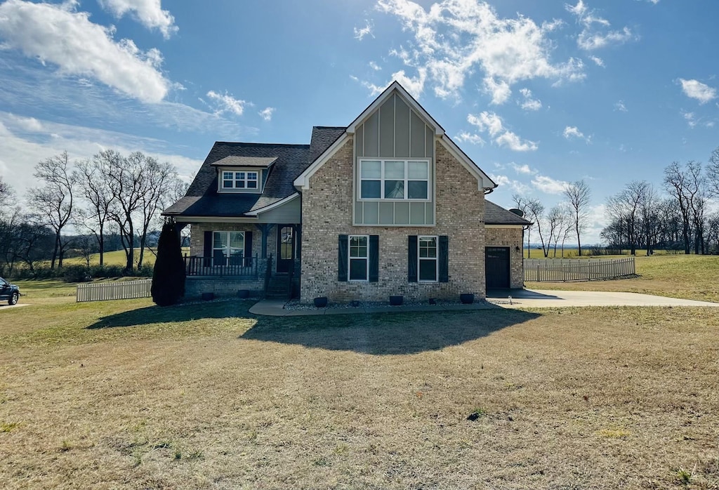 view of front of home featuring a porch, a garage, and a front yard