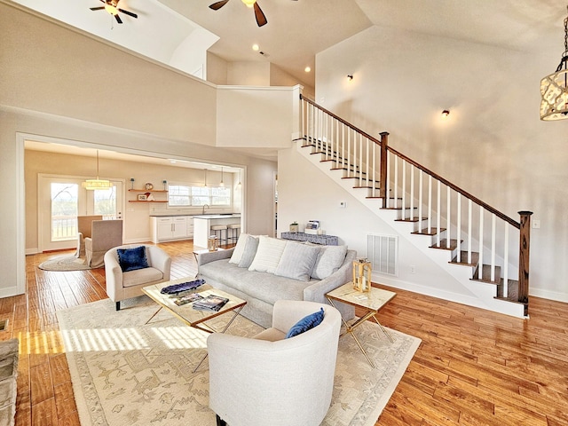 living room with ceiling fan, high vaulted ceiling, and light wood-type flooring