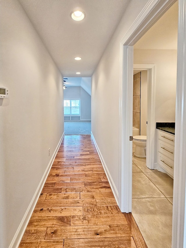 hall with lofted ceiling and light hardwood / wood-style floors