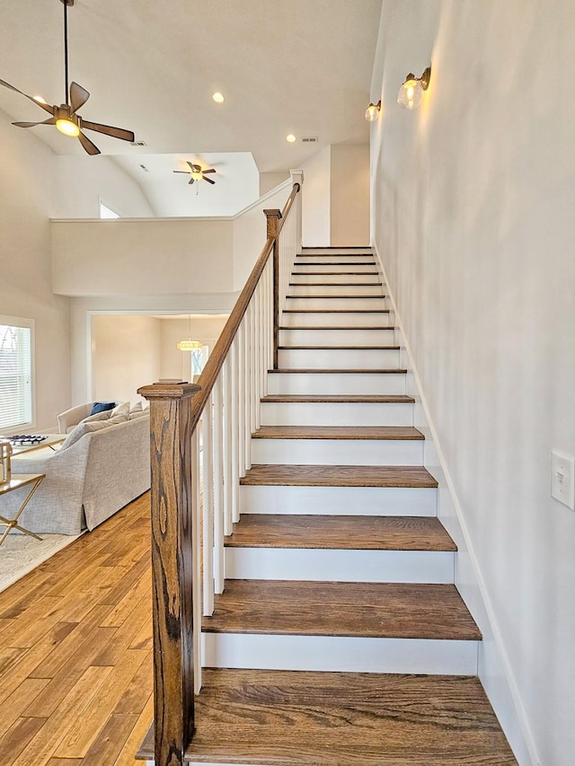 stairway with wood-type flooring and ceiling fan