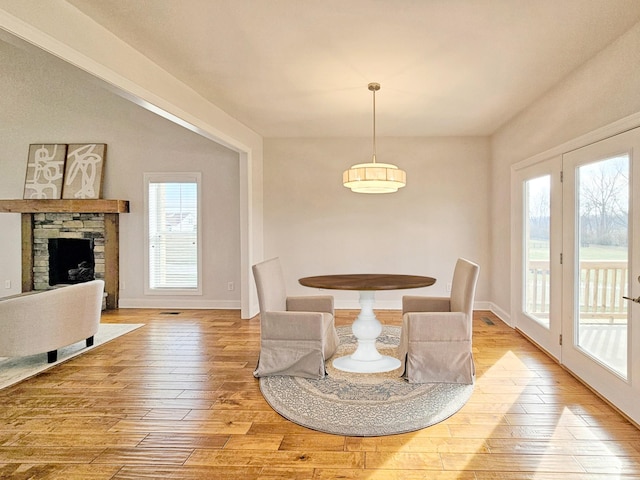 dining room featuring a stone fireplace and light wood-type flooring