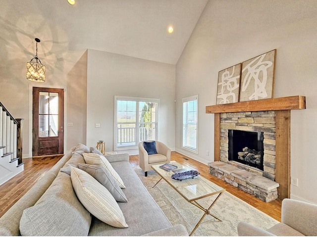 living room featuring high vaulted ceiling, a fireplace, and light wood-type flooring