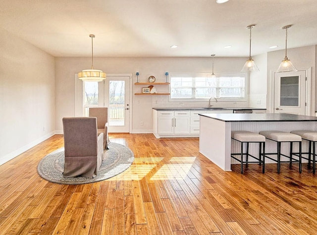 kitchen featuring light wood-type flooring, sink, tasteful backsplash, and white cabinets