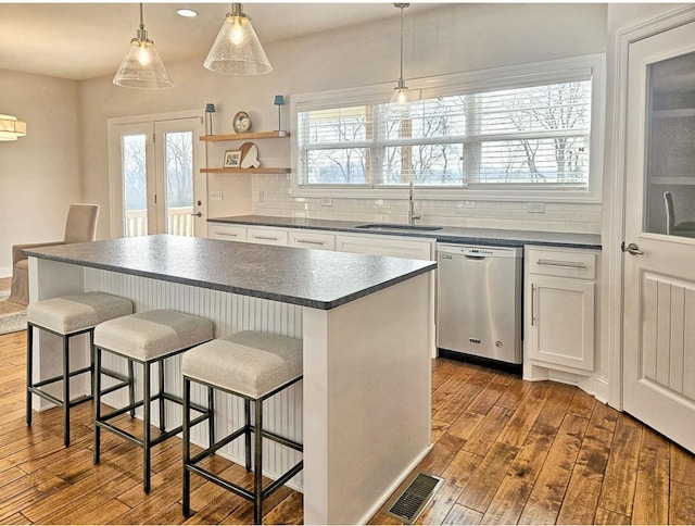 kitchen with a kitchen island, decorative light fixtures, dishwasher, sink, and white cabinets