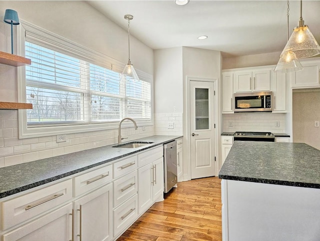 kitchen featuring hanging light fixtures, appliances with stainless steel finishes, sink, and white cabinets