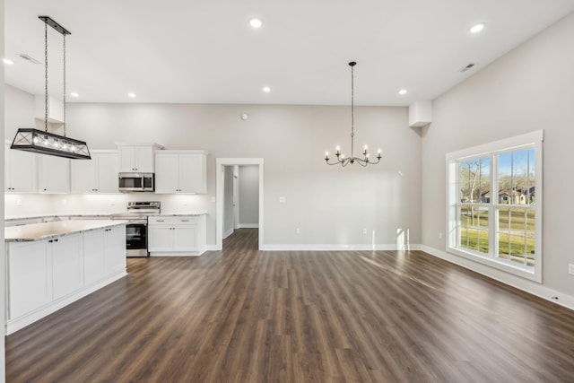 kitchen with pendant lighting, dark wood-type flooring, white cabinetry, stainless steel appliances, and light stone counters