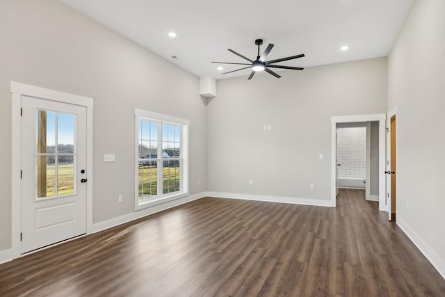 unfurnished living room with a towering ceiling, dark hardwood / wood-style floors, and ceiling fan