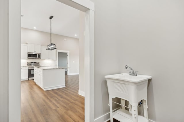 kitchen featuring a breakfast bar area, hanging light fixtures, light wood-type flooring, stainless steel appliances, and white cabinets