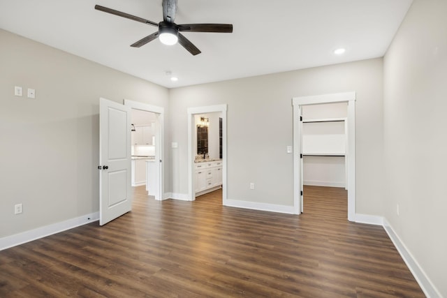 unfurnished bedroom with ceiling fan, ensuite bath, a spacious closet, and dark hardwood / wood-style flooring