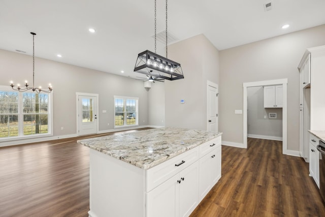 kitchen featuring light stone counters, dark hardwood / wood-style floors, a center island, and white cabinets