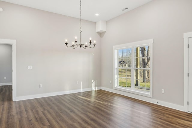 unfurnished dining area with an inviting chandelier and dark hardwood / wood-style flooring