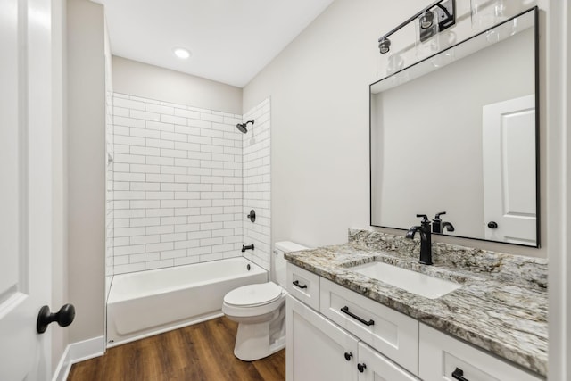 full bathroom featuring tiled shower / bath, wood-type flooring, vanity, and toilet