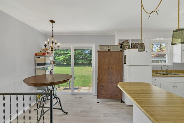 dining area featuring ornamental molding, a chandelier, sink, and light wood-type flooring