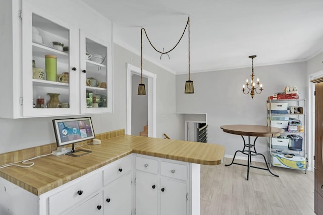 kitchen featuring hanging light fixtures, white cabinetry, and ornamental molding